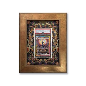 Peut inclure: Une carte Pokémon encadrée avec une illustration colorée. La carte est protégée dans un étui, sur un fond à motifs. Le cadre doré métallique ajoute une touche d'élégance à ce collectible.
