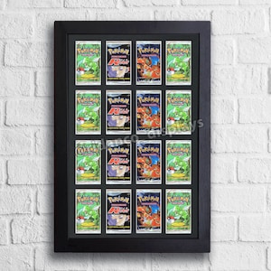 May include: A black frame with a white mat displays 16 Pokemon trading cards. The cards are arranged in a 4x4 grid. Each card features a different Pokemon character, including Venusaur, Charizard, and Blastoise. The cards are in excellent condition and are protected by the frame.
