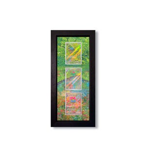 Op de afbeelding: Een zwart omkaderde display met drie verzamelkaarten. De kaarten staan tegen een kleurrijke, abstracte achtergrond met groene, blauwe en rode tinten. De kaarten hebben holografische details en zitten in beschermhoezen.