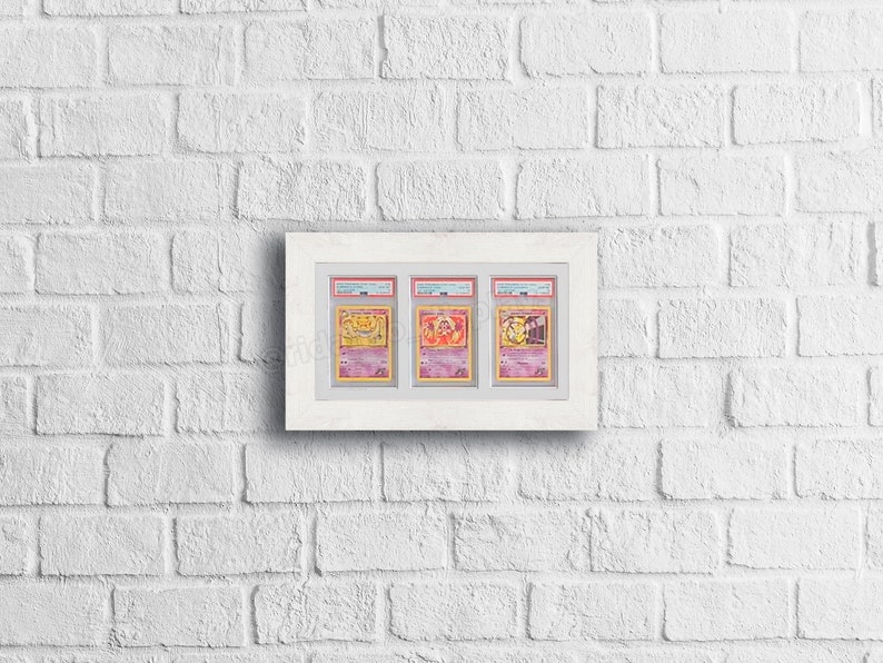 May include: Three Pokemon trading cards are displayed in a white frame. The cards are encased in protective plastic sleeves and feature the characters Charizard, Blastoise, and Venusaur.