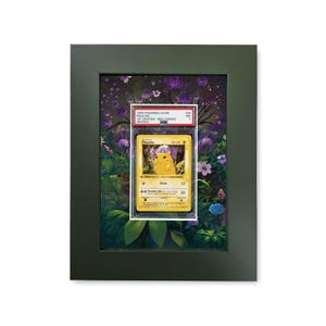 Op de afbeelding: Ingelijste Pokémon-kaart met Pikachu. De kaart zit in een beschermende houder en tegen een bloemenachtergrond. De lijst is donkergroen en de kaart is getiteld "1999 Pokemon Game Pikachu 1st Edition - Red Cheeks".