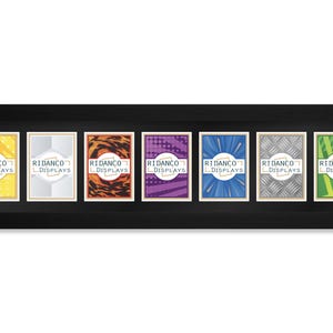 Op de afbeelding: Een zwart omkaderde display met zeven kleurrijke kaarten. Elke kaart heeft een uniek ontwerp en de tekst "RIDANCO DISPLAYS". De kaarten hebben gele, witte, oranje, paarse, blauwe, grijze en groene achtergronden.