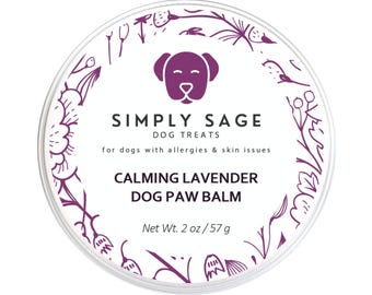 May include: A round container of Simply Sage Calming Lavender Dog Paw Balm. The label features a purple dog graphic and text, including "for dogs with allergies & skin issues." Net weight is 2 oz / 57 g.