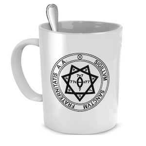 May include: White ceramic mug with a black and white image of a sigil with the text "FRATERNITATIS A.A.: SIGILLVM SANCTVM" around the outside.