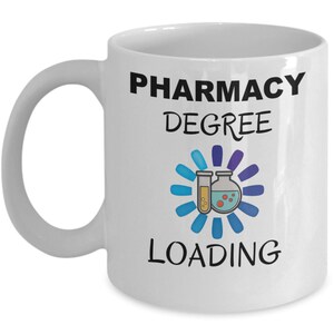 May include: White ceramic coffee mug with black text that reads "Pharmacy Degree Loading" and a graphic of a beaker and test tube with a blue loading circle around them.