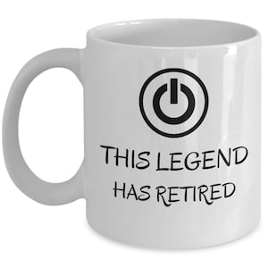 以下が含まれることがあります： 黒い電源ボタンのシンボルと「This Legend Has Retired」というテキストが書かれた白いセラミック製のコーヒーカップです。