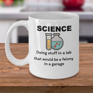 May include: White ceramic coffee mug with a black and white graphic that says "SCIENCE" with a beaker and test tube. The text below the graphic says "Doing stuff in a lab that would be a felony in a garage."