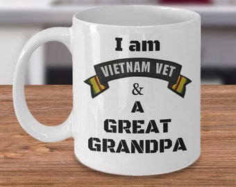 May include: White ceramic coffee mug with black text that reads "I am Vietnam Vet & A Great Grandpa". The text is in a banner with a yellow and green stripe on each side.