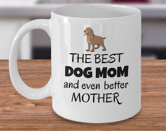 May include: White ceramic coffee mug with a brown dog illustration and the text "The Best Dog Mom and even better Mother".