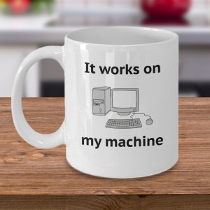 Puede incluir: Taza de cerámica blanca con un contorno negro de una computadora y el texto "It works on my machine".
