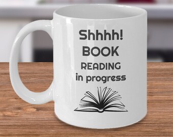 May include: White ceramic coffee mug with a black graphic that says "Shhhh! Book Reading in progress" and a black illustration of an open book.