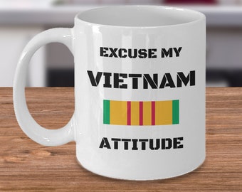 May include: White ceramic coffee mug with black text that reads "Excuse my Vietnam attitude". A green, yellow, and red ribbon is printed below the text.