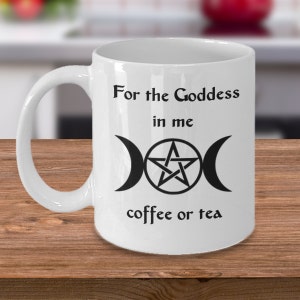 May include: White ceramic mug with black text and a black triple moon symbol with a pentagram inside. The text reads "For the Goddess in me coffee or tea".