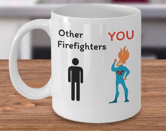 Puede incluir: Taza de café de cerámica blanca con una ilustración en blanco y negro de una figura de palo y el texto "Other Firefighters". En el lado derecho de la taza hay una ilustración de dibujos animados de un superhéroe con llamas para el cabello y el texto "YOU" en rojo.