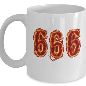 May include: White ceramic coffee mug with the number 666 in fiery orange and red flames.