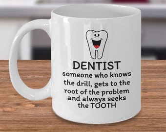 May include: White ceramic coffee mug with a black and white illustration of a smiling tooth. The mug has the text "DENTIST someone who knows the drill, gets to the root of the problem and always seeks the TOOTH".