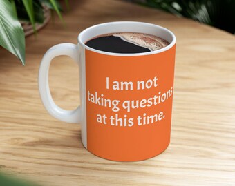 ROROTOKO I am not taking questions at this time Mug. Orange text ceramic coffee cup