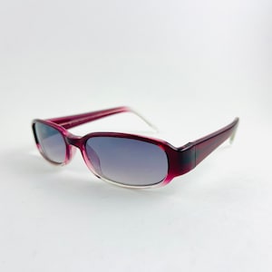 Peut inclure: Une paire de lunettes de soleil de couleur bordeaux avec une monture transparente et des verres gris foncé.