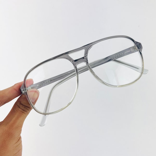 May include: Clear grey plastic aviator style eyeglasses with a silver metal nose bridge.