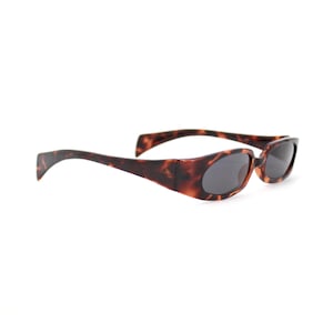 May include: Tortoiseshell sunglasses with dark lenses. The sunglasses have a rectangular shape and a curved frame. The frame is a mix of brown and black colors. The sunglasses are set against a white background.