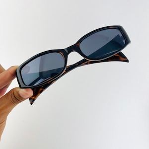 May include: Tortoise shell sunglasses with black frames and dark lenses.
