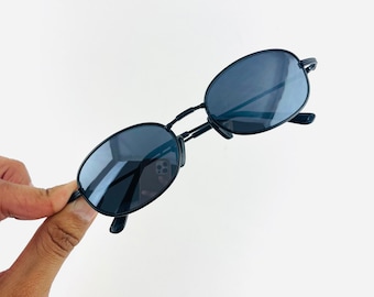 May include: Black oval-shaped sunglasses with thin metal frames.