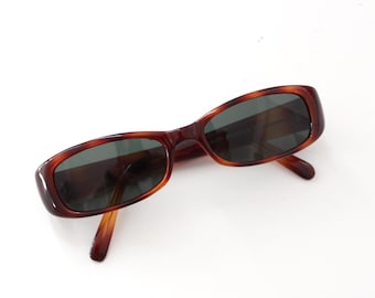 Könnte beinhalten: Schildpatt-Sonnenbrille mit dunklen Gläsern. Die Sonnenbrille hat eine rechteckige Form.