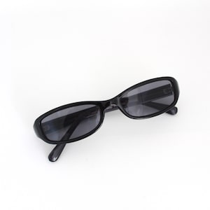 Könnte beinhalten: Schwarze, ovale Sonnenbrille mit dunklen Gläsern.