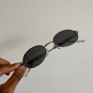 May include: Silver oval-shaped sunglasses with black lenses.