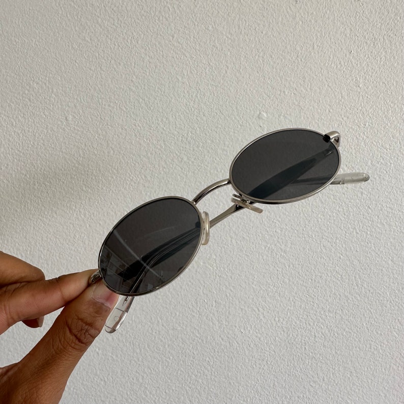 May include: Silver oval-shaped sunglasses with black lenses.