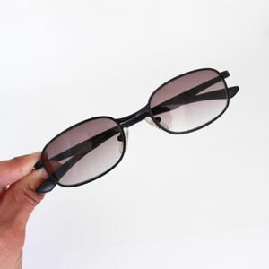 Peut inclure: Lunettes de soleil rectangulaires noires avec des verres dégradés brun foncé.