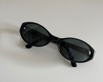 May include: Black oval sunglasses with dark lenses.
