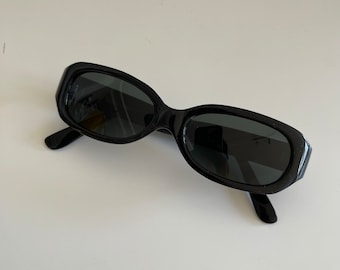 Puede incluir: Gafas de sol ovaladas negras con lentes oscuros.
