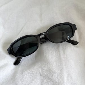 May include: Black oval-shaped sunglasses with dark lenses.