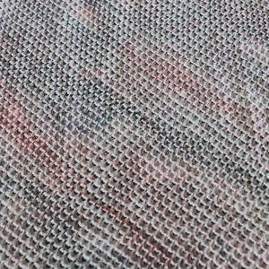May include: Close-up of a woven fabric with a textured pattern. The fabric is a mix of white, black, and red.