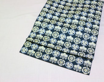 May include: A folded piece of dark blue fabric with a repeating pattern of gold and white stylized flowers. The fabric has a subtle sheen.