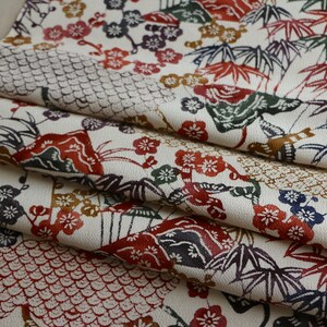 May include: Folded fabric with a cream background and a repeating pattern of Japanese-style motifs. The design includes red, green, and purple bamboo leaves, flowers, and geometric shapes.