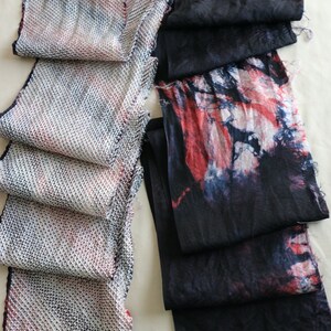 May include: Two fabric strips, one with a white and pink woven pattern and the other with a black and red tie-dye pattern.
