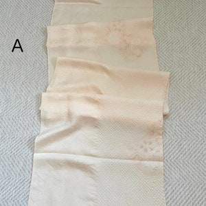 May include: A long, off-white fabric with a subtle embossed pattern. The fabric is folded in thirds and has a slight sheen.