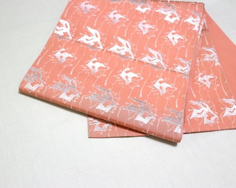 May include: A pink fabric with a white floral pattern. The fabric is folded in half and the pattern is visible on both sides.