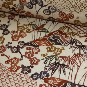 May include: Cream-colored fabric with a repeating pattern of Japanese-style illustrations. The design features plum blossoms, bamboo, and stylized mountains in shades of red, brown, purple, and green. The fabric is likely used for clothing or home decor.