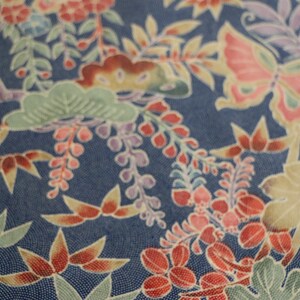 May include: A blue fabric with a floral pattern featuring butterflies, leaves, and flowers in shades of red, pink, white, and green.