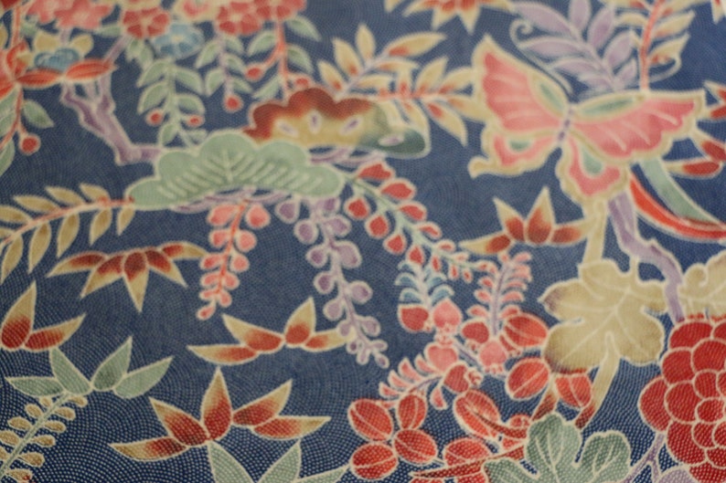 May include: A blue fabric with a floral pattern featuring butterflies, leaves, and flowers in shades of red, pink, white, and green.