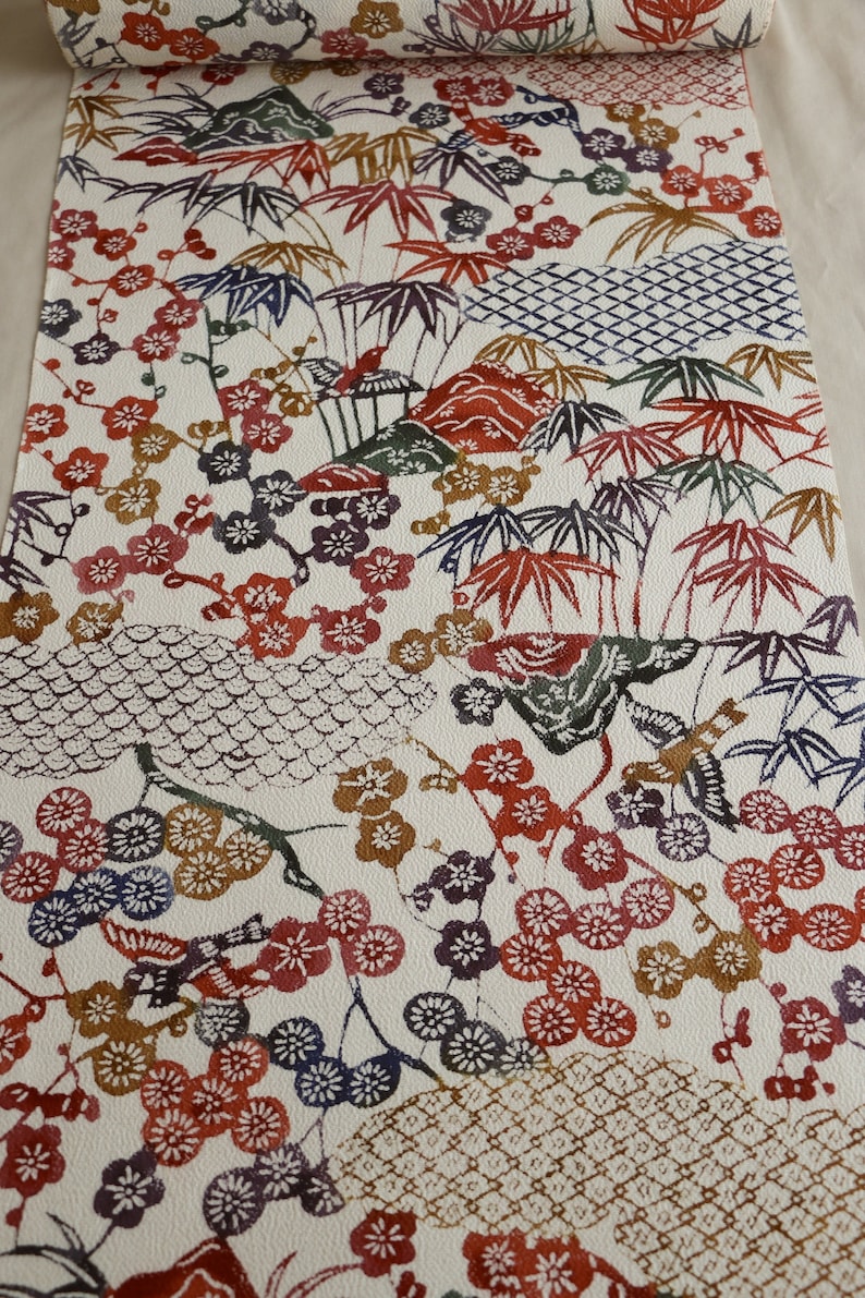 May include: A roll of patterned fabric featuring a Japanese-inspired design. The off-white background is adorned with red, purple, and brown floral and foliage motifs, including cherry blossoms and bamboo. The design also incorporates geometric patterns.