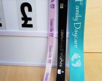 May include: Three satin ribbons with different text printed on them. The first ribbon is pink with purple text that says "Gracies Gifts off". The second ribbon is black with gold text that says "candlelit wishes". The third ribbon is turquoise blue with white text that says "Board Family Daycare".