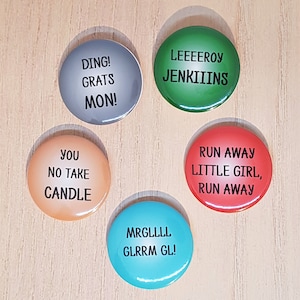 May include: Five round buttons with different colours and text. The buttons are grey, green, orange, red, and blue. The text on the buttons reads: "DING! GRATS MON!" "LEEEEROY JENKIIINS" "YOU NO TAKE CANDLE" "RUN AWAY LITTLE GIRL, RUN AWAY" "MRGLLLL GLRRM GL!"
