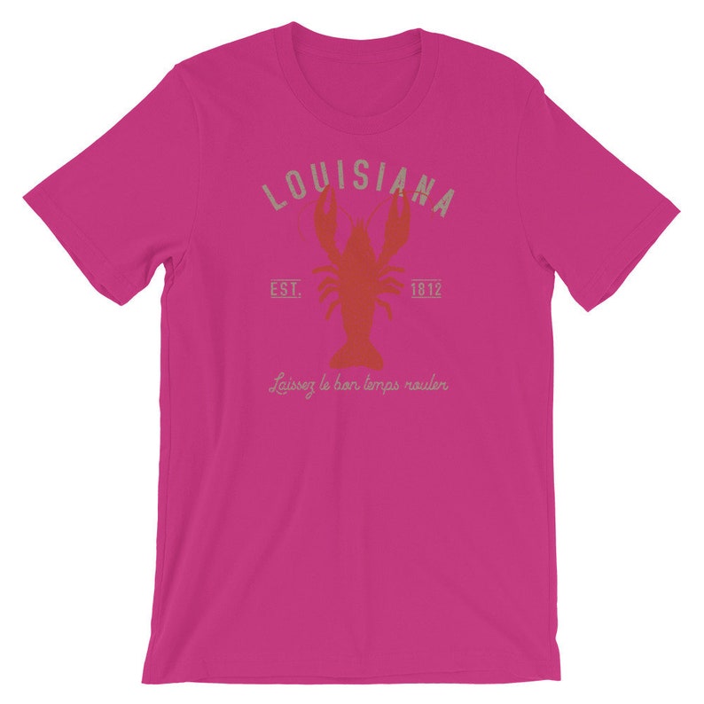 Op de afbeelding: Een roze T-shirt met een vintage-stijl grafische afbeelding van een kreeft en de tekst "Louisiana Est. 1812" en "Laissez le bon temps rouler".