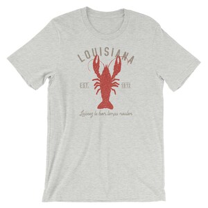 Op de afbeelding: Een grijs T-shirt met een rode kreeft illustratie en de tekst "Louisiana Est. 1812" en "Laissez le bon temps rouler".