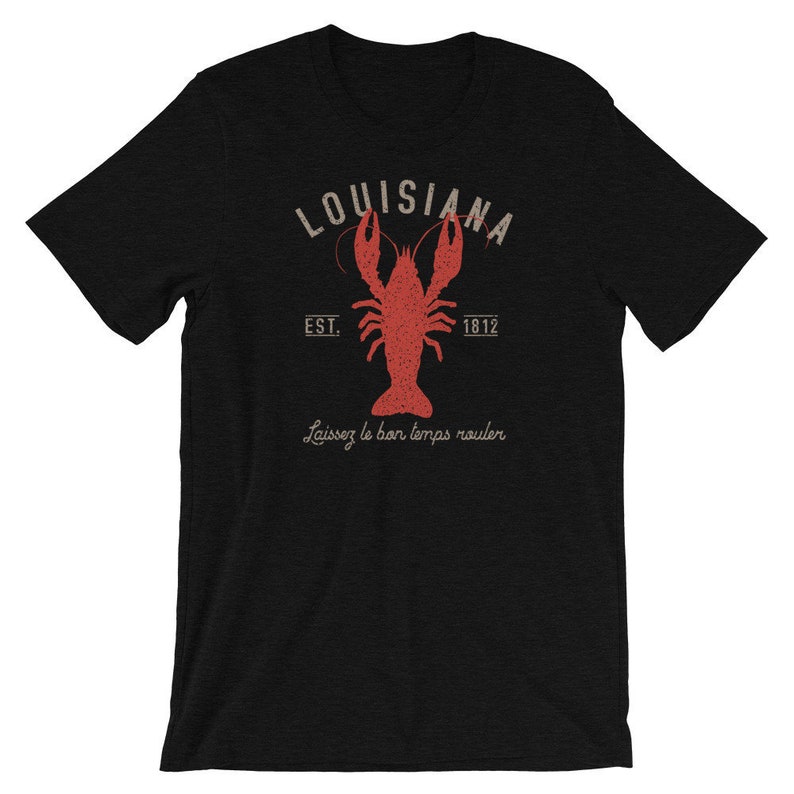 Op de afbeelding: Zwart T-shirt met een rode kreeft illustratie en de tekst "Louisiana Est. 1812" en "Laissez le bon temps rouler" in een vintage lettertype.
