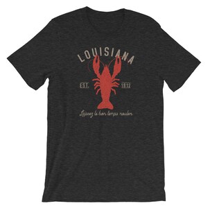 Op de afbeelding: Een donkergrijs T-shirt met een vintage-stijl grafische afbeelding van een rode kreeft, de tekst "Louisiana" in een witte cirkel en de tekst "Est. 1812" onder de cirkel. De tekst "Laissez le bon temps rouler" is onder de kreeft gedrukt.
